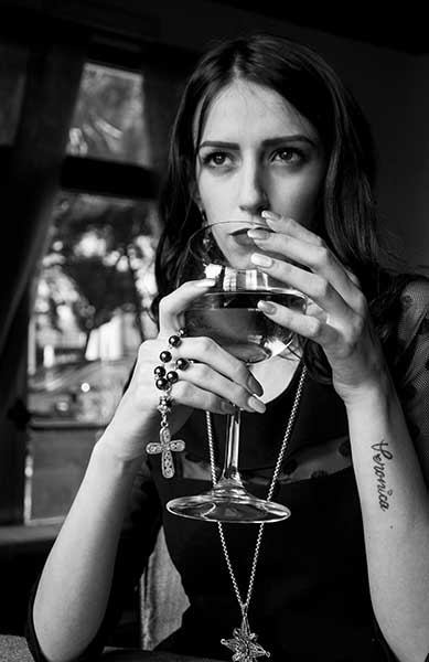 foto in bianco nero di una modella che sorseggia un bicchiere di vino bianco mostrando il suo gioiello in filigrana